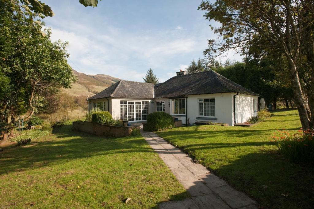 ein kleines weißes Haus mit einem Rasenplatz in der Unterkunft Highland cottage Fort William in Fort William