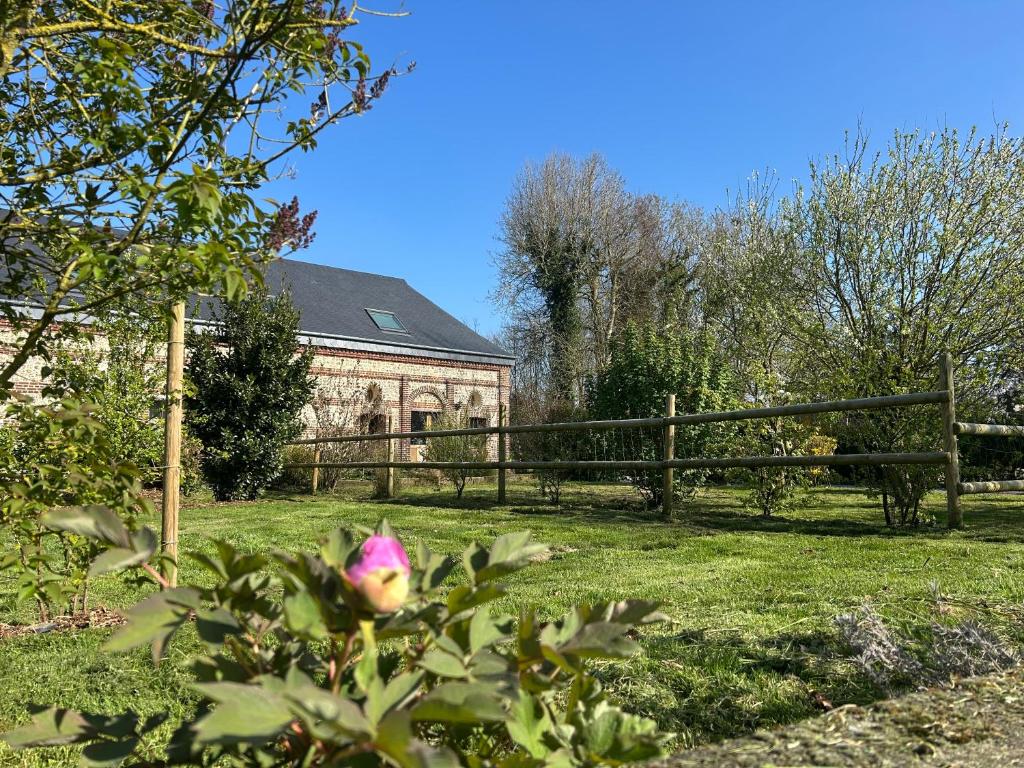 une fleur rose devant une clôture et un banc dans l'établissement L'Echo de la nature, à Sasseville