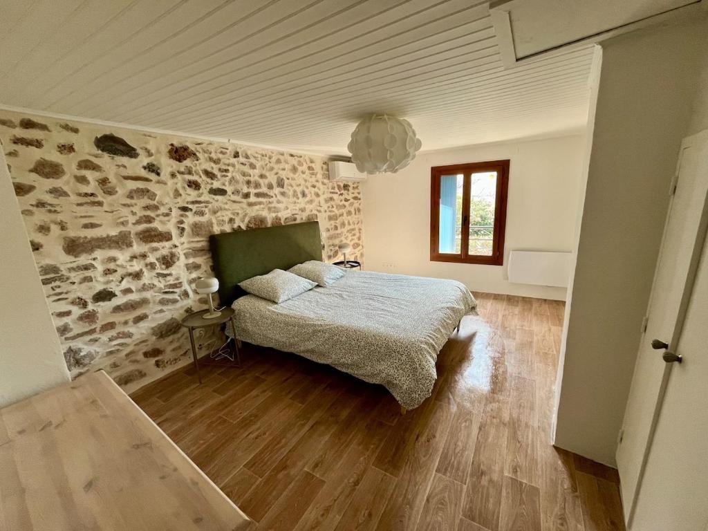 a bedroom with a bed and a stone wall at Charmante maison dans un hameau paisible in Salasc