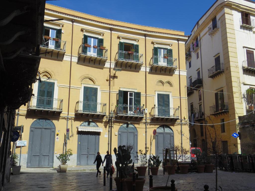 un edificio amarillo con gente caminando delante de él en Home Maletto, en Palermo
