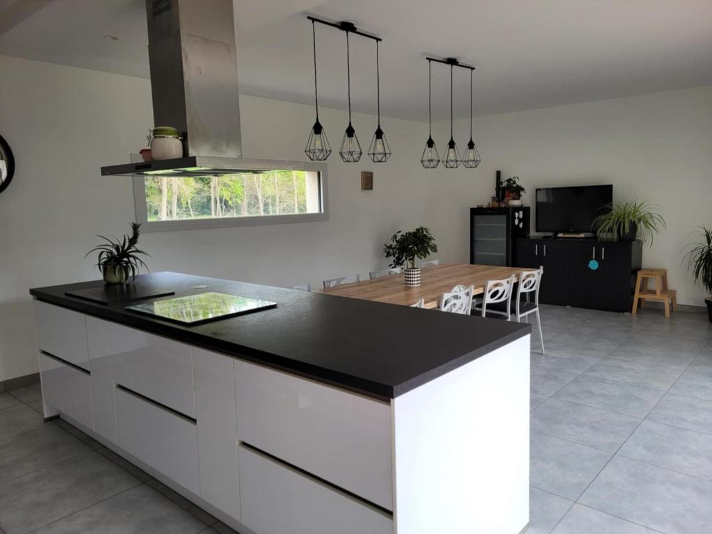 une cuisine avec un comptoir noir et une table dans l'établissement Maison récente 200m2 proche du circuit du Mans au calme, à Changé