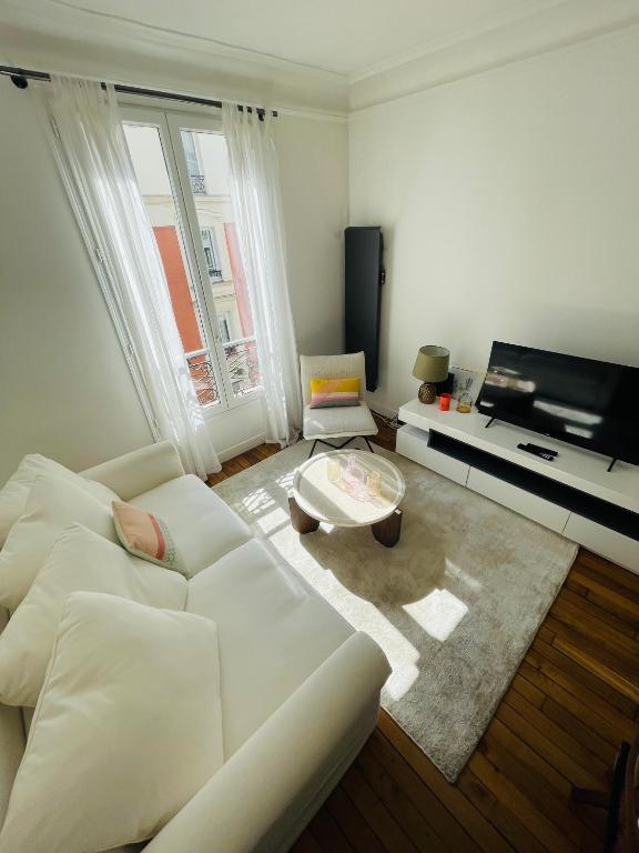 un salon avec un canapé blanc et une télévision dans l'établissement Luxueux 2 pièces au cœur du 16e, à Paris