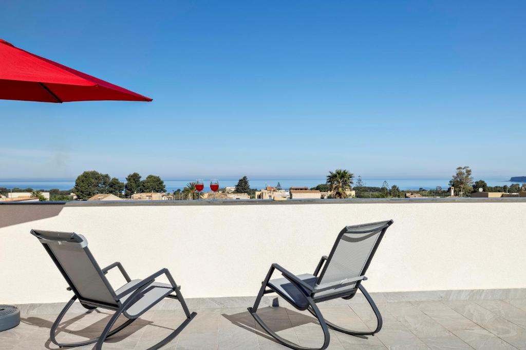 two chairs sitting next to a wall with the ocean at Case Vacanza Loria in Castelluzzo
