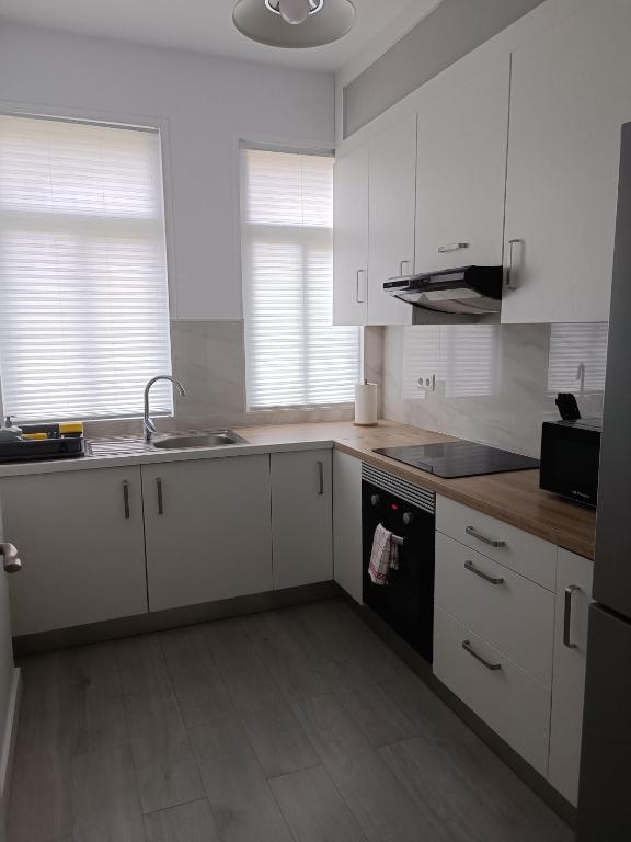 a kitchen with white cabinets and a sink and a stove at Entresuelo luminoso cerca de Escaño in Ferrol