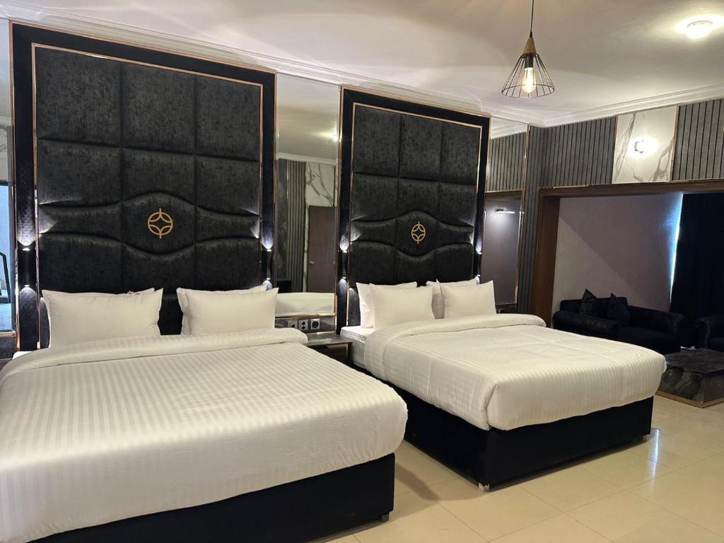 a bedroom with two beds and a living room at Hotel Oasis in Islamabad