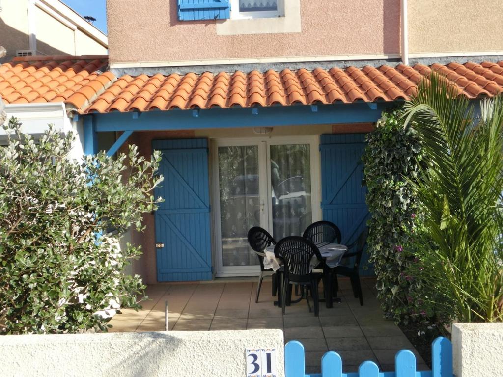 une maison bleue avec un chat assis sur une terrasse dans l'établissement Charmantes Ferienhäuschen in Strandnähe, à Gruissan