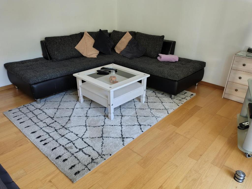 a living room with a black couch and a coffee table at City Apartment WOB-Rothenfelde in Wolfsburg