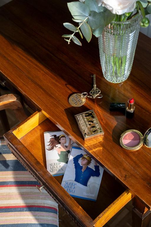 a wooden table with a clock and a vase of flowers at Palace Hotel in Viareggio