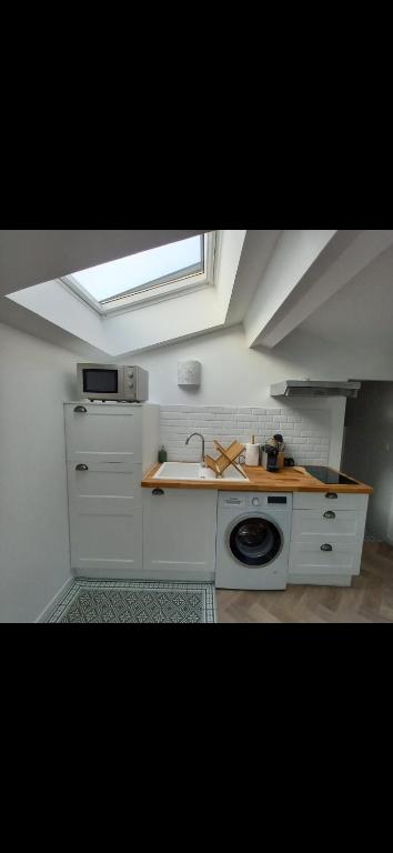 une cuisine blanche avec un évier et une fenêtre dans l'établissement La Maunia Studio, à Montceaux