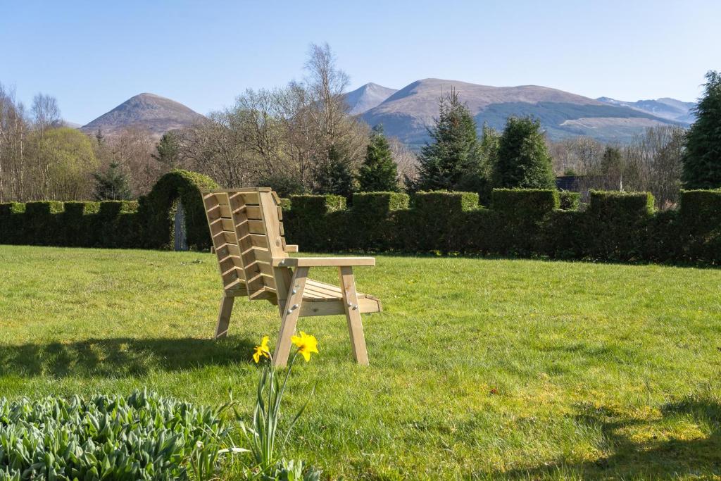 a chair sitting in the grass in a field at Mizpah Bed & Breakfast near Ben Nevis Highlands in Roybridge