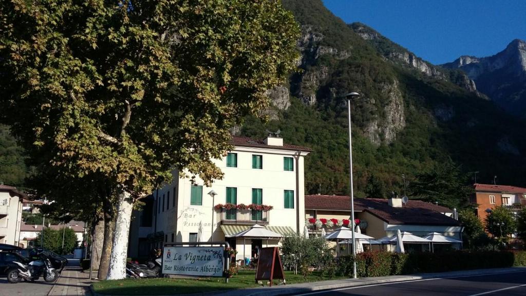 ein weißes Gebäude mit einem Baum vor einem Berg in der Unterkunft La Vigneta in Arsiero