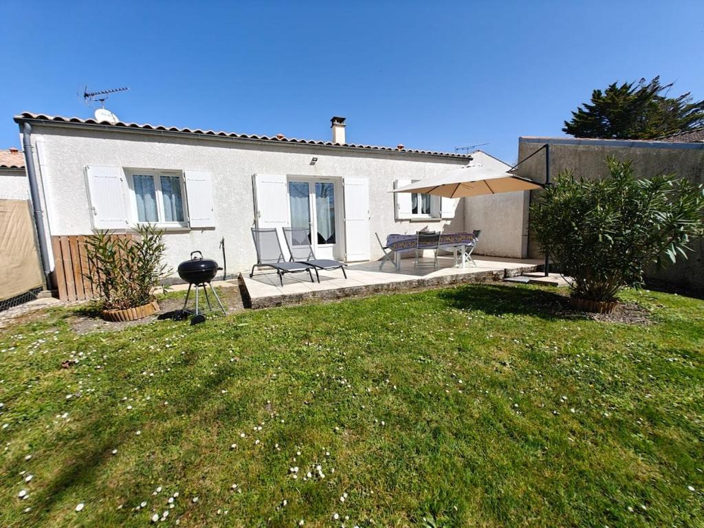 une maison blanche avec une cour et une terrasse dans l'établissement L 'escapade d 'Arvert, à Arvert