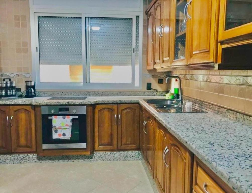 een keuken met houten kasten en een kookplaat met oven bij Apartamento hay amal 12 in Sale