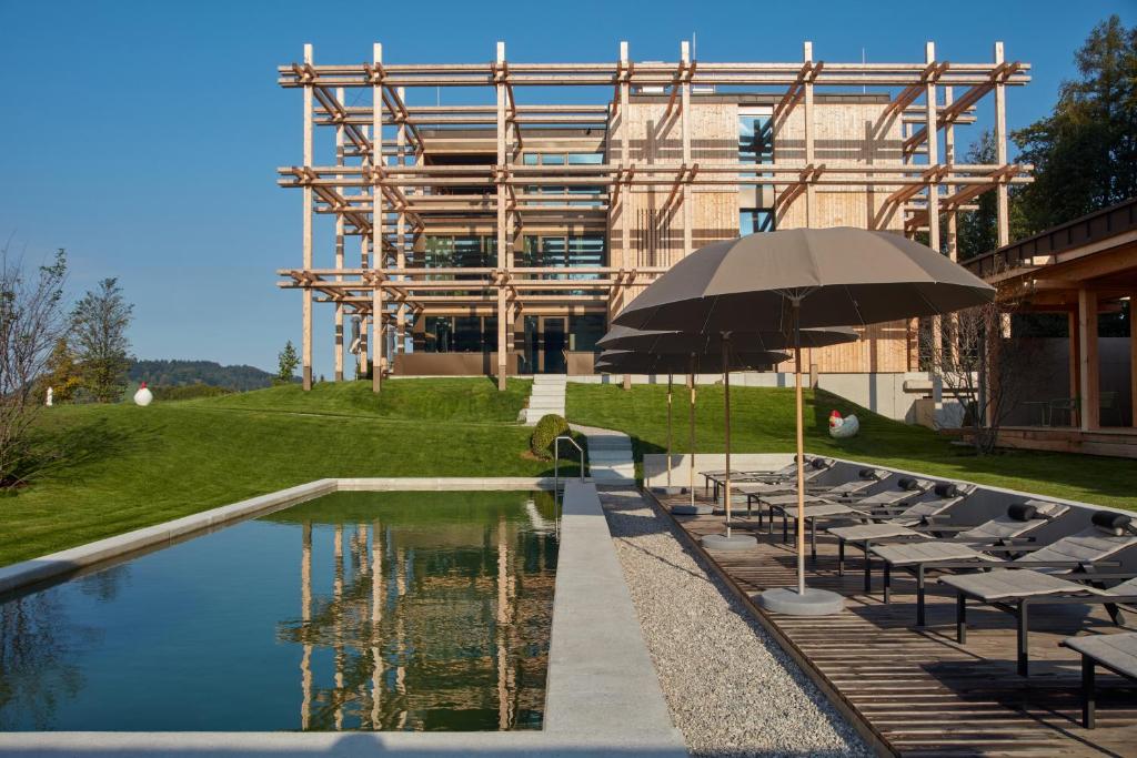 Una piscina con sillas y una sombrilla al lado de un edificio. en Hotel BERGEBLICK, en Bad Tölz