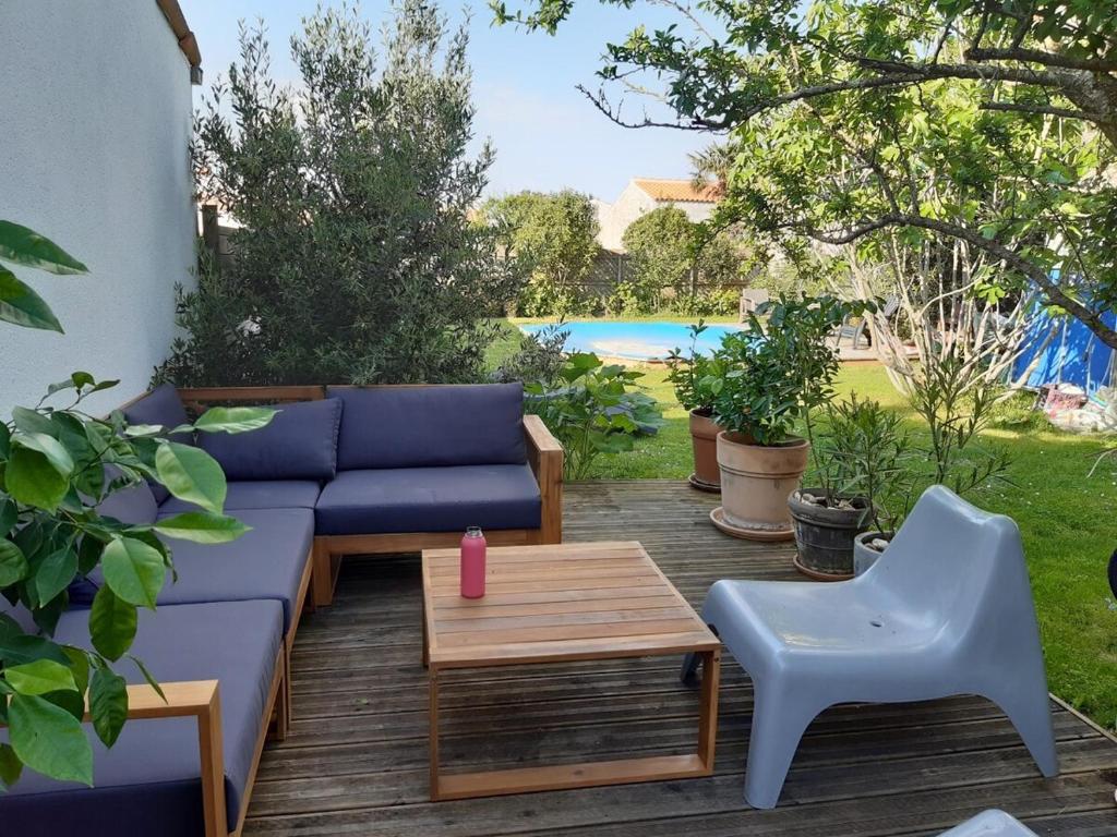 une terrasse avec un canapé bleu, une table et des chaises dans l'établissement Spacious house, ideally located with pool!, à Rochefort