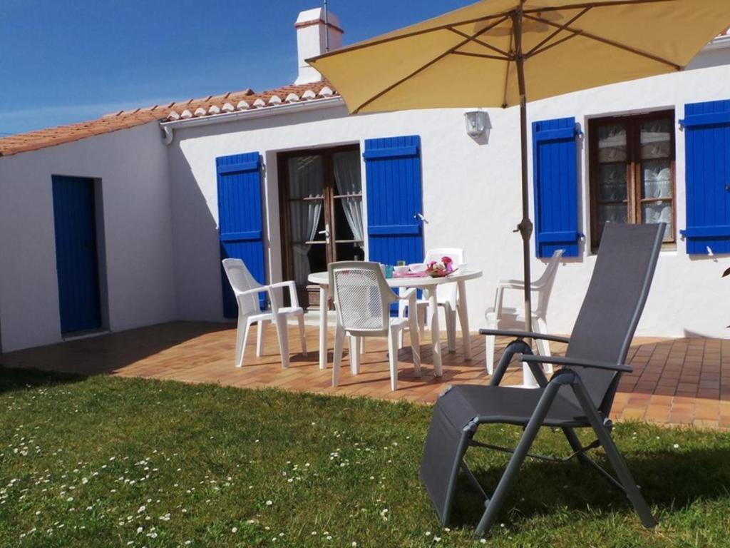 un patio avec une table, des chaises et un parasol dans l'établissement Maison 3 pièces avec jardin, proche plage à Noirmoutier - FR-1-224B-681, à Noirmoutier-en-l'lle