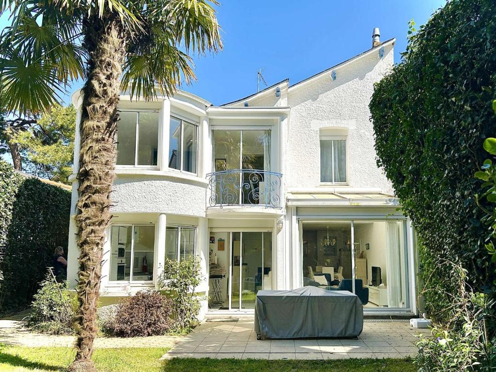 une grande maison blanche avec une table en face dans l'établissement Villa Bauloise 5 pièces, 8 couchages, proche marché, plage, jardin, parking, BBQ - FR-1-245-131, à La Baule