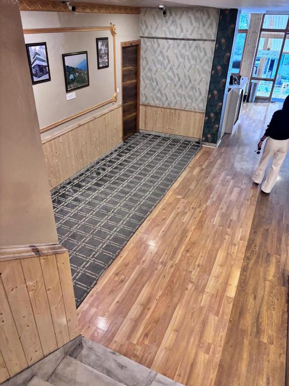 a person standing in a room with a hard wood floor at Shobha Hotel in Manāli