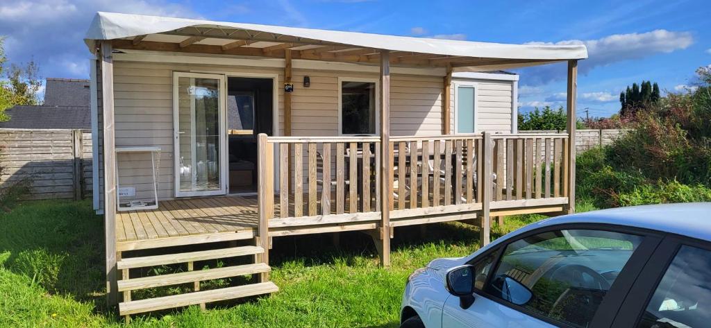 Ce chalet en bois dispose d'une terrasse avec un toit. dans l'établissement Mobil-home 28 m2, 2 chambres et terrasse, à Douarnenez