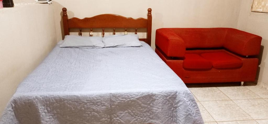 um quarto com uma cama e uma cadeira vermelha em Residencial Barbosa - Apto 301 em Macaé