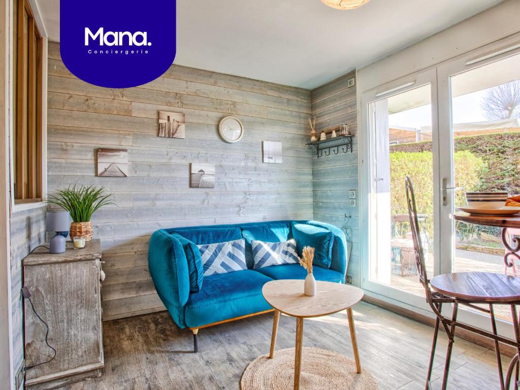 ein Wohnzimmer mit einem blauen Sofa und einem Tisch in der Unterkunft Les Dunes - Jardin Privatif - Plage à 500 Mètres in Merville-Franceville-Plage