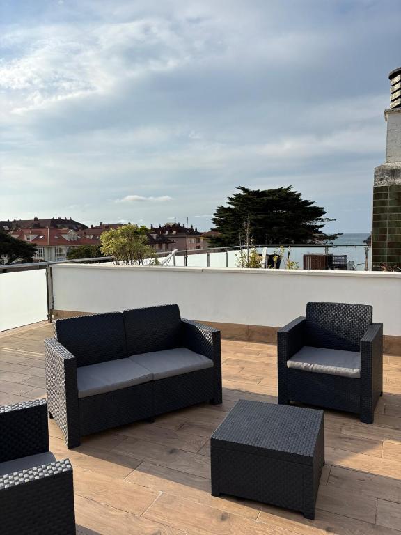 a patio with two chairs and a couch on a roof at Casa Mouro Somo - Surf y playa in Somo