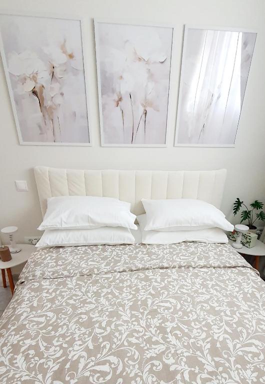 a bedroom with a bed with two paintings on the wall at Jasmine Home, Aegina City in Egina