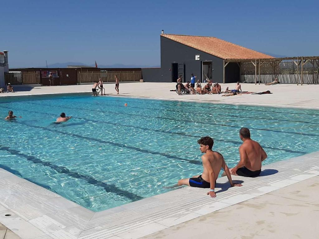 un groupe de personnes assises dans une piscine dans l'établissement Duplex familial 2 chambres avec piscine et parking, accès lac - FR-1-782-55, au Barcarès