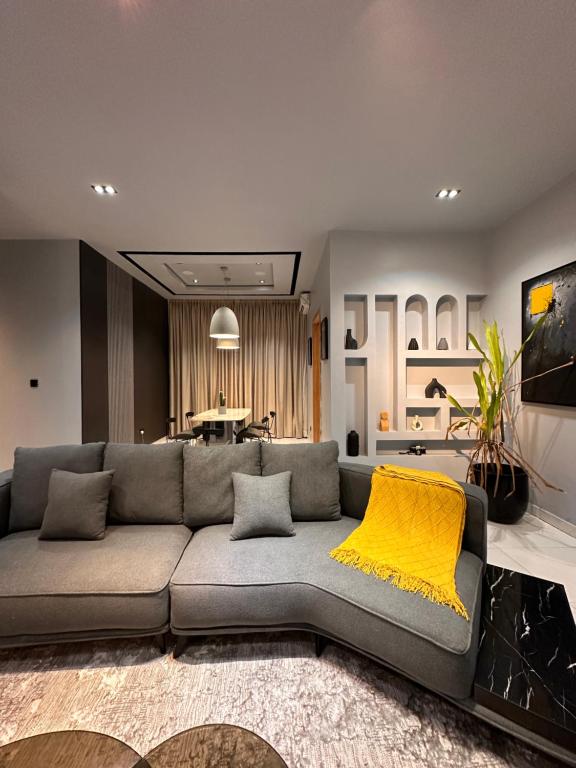 Una sala de estar con un sofá gris y una manta amarilla. en emerald, en Lagos