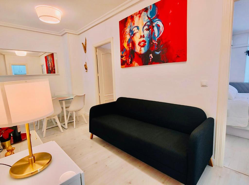 ein Wohnzimmer mit einem schwarzen Sofa und einem Gemälde an der Wand in der Unterkunft En PLENO CENTRO - Especial para GRUPOS o FAMILIAS - GRAN VÍA - CALLAO - SOL - PLAZA ESPAÑA in Madrid