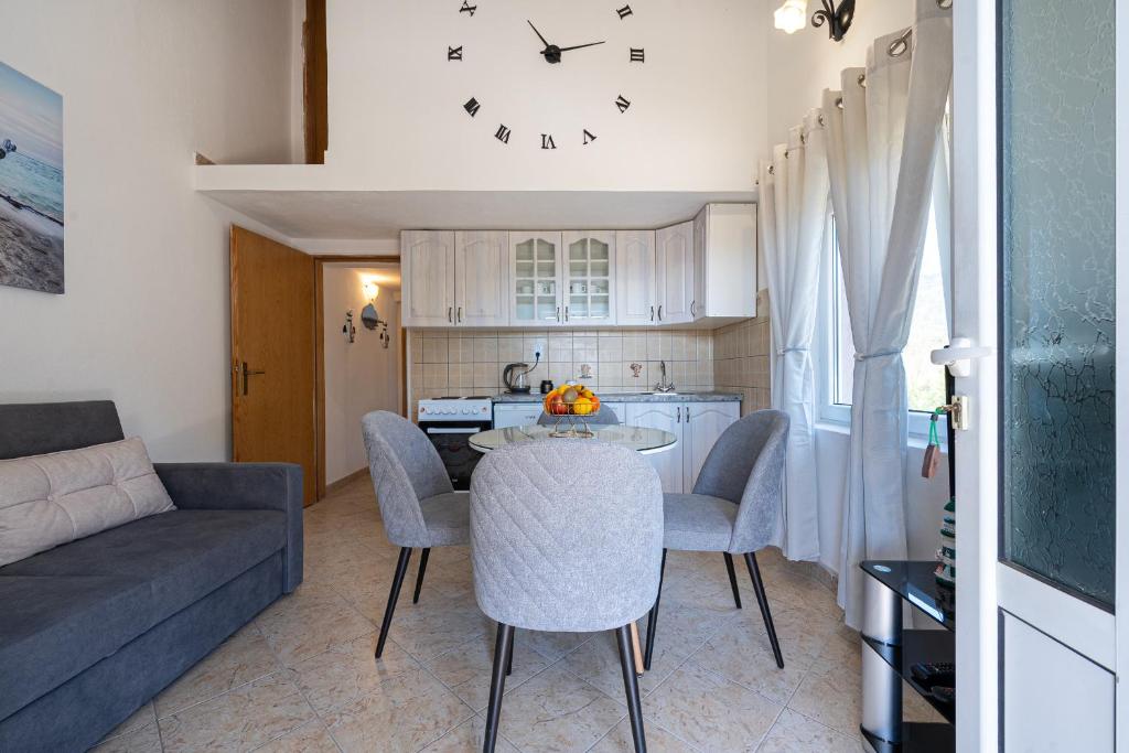a living room with a table and a clock on the wall at Apartments Ivo Bozinovic in Tivat