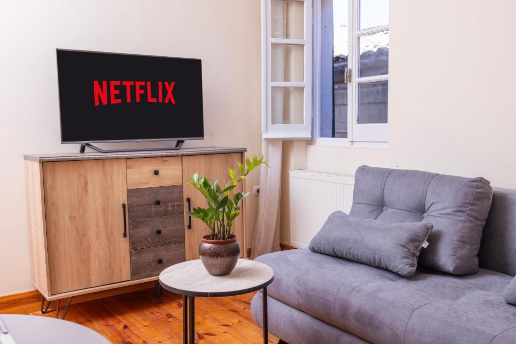 a living room with a couch and a tv on a cabinet at Mouragia Budget Places in Corfu Town