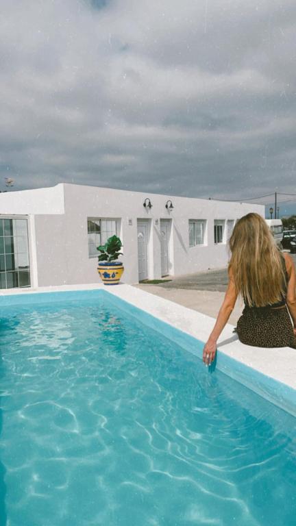 a woman sitting on the edge of a swimming pool at Casa Elenita in La Oliva