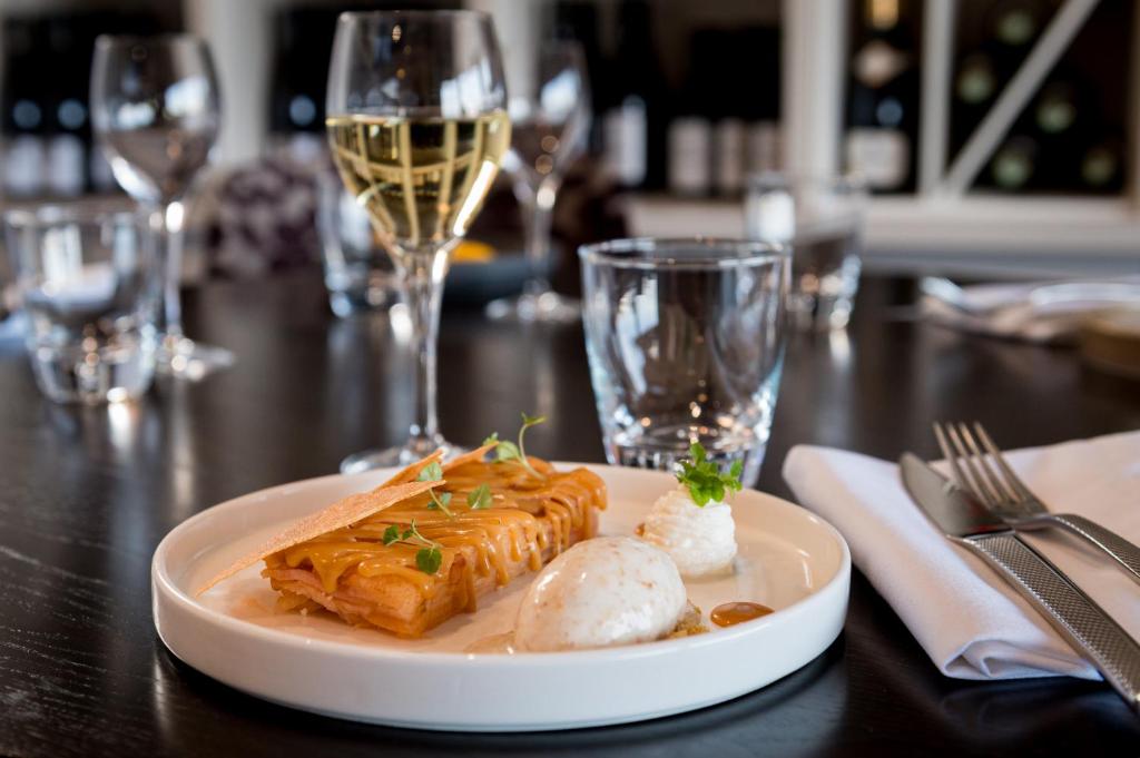 a plate of food on a table with wine glasses at Saint Aubin Logis Hôtel & Restaurant in Saint-Aubin-sur-Mer