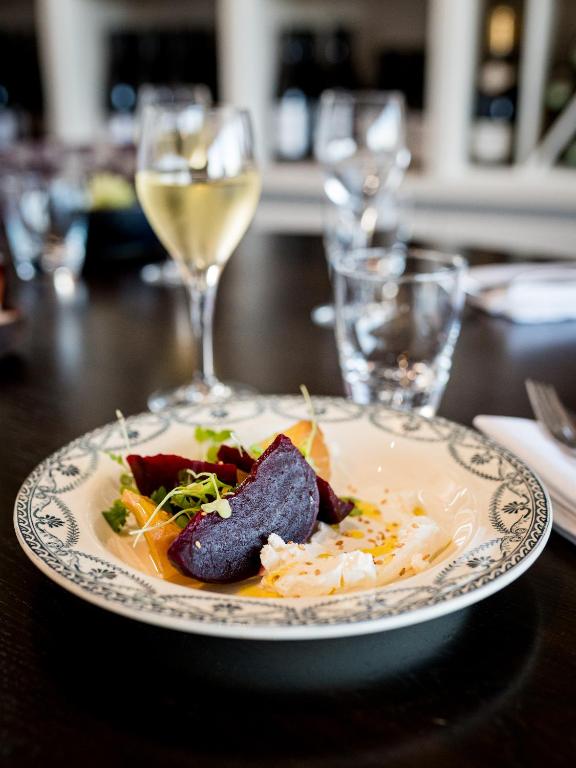 a plate of food on a table with wine glasses at Saint Aubin Logis Hôtel & Restaurant in Saint-Aubin-sur-Mer