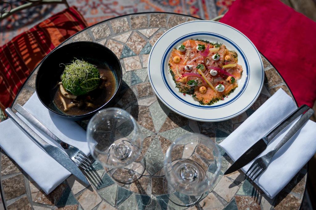 a table with a plate of food and a bowl of food at Saint Aubin Logis Hôtel & Restaurant in Saint-Aubin-sur-Mer