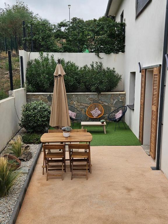 un patio avec une table, des chaises et un parasol dans l'établissement Appartement bas de villa avec accès piscine, à Ventiseri