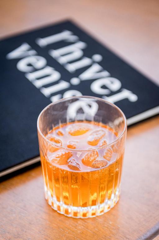 a glass of orange soda sitting on a table at Saint Aubin Logis Hôtel & Restaurant in Saint-Aubin-sur-Mer
