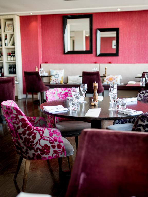 a restaurant with tables and chairs and pink walls at Saint Aubin Logis Hôtel & Restaurant in Saint-Aubin-sur-Mer