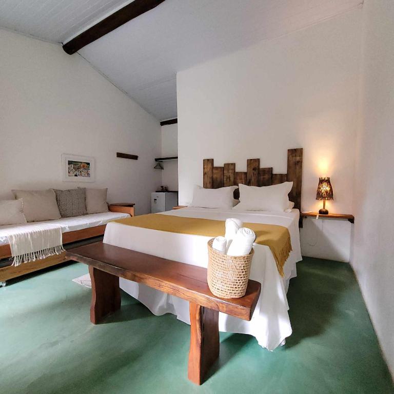 a large bedroom with two beds and a table at Suítes Aracuã in Caraíva