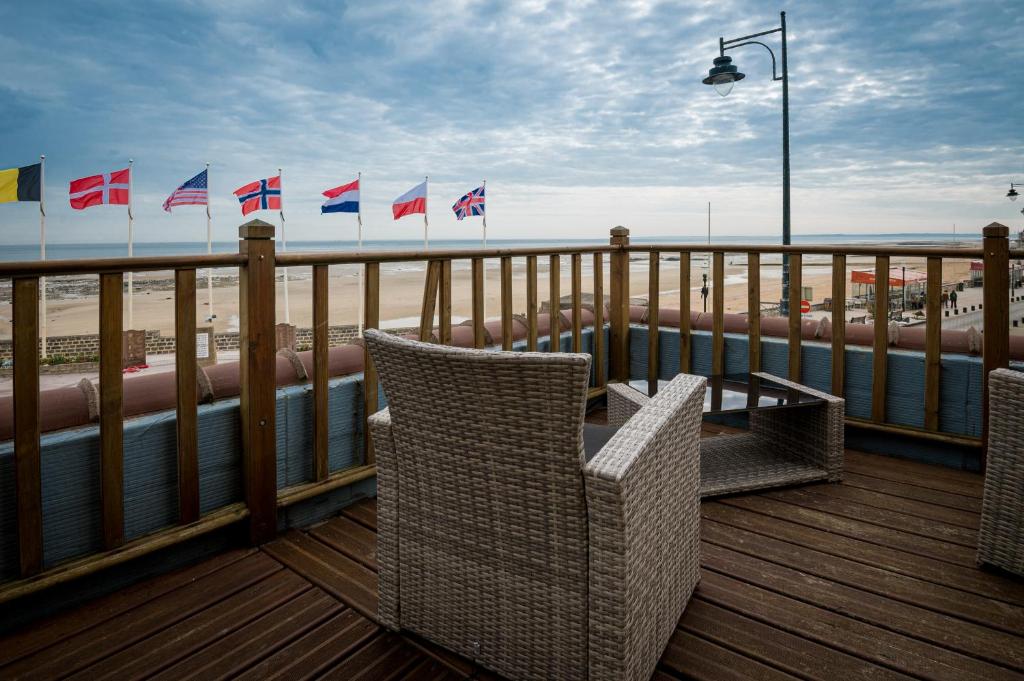 a deck with chairs and flags on the beach at Saint Aubin Logis Hôtel & Restaurant in Saint-Aubin-sur-Mer