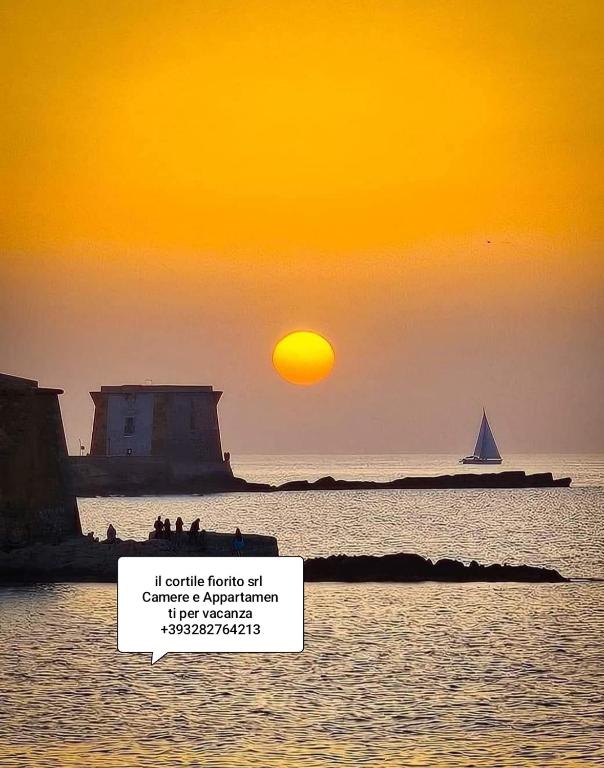 a sunset over the ocean with a boat in the water at Il Cortile Fiorito in Trapani