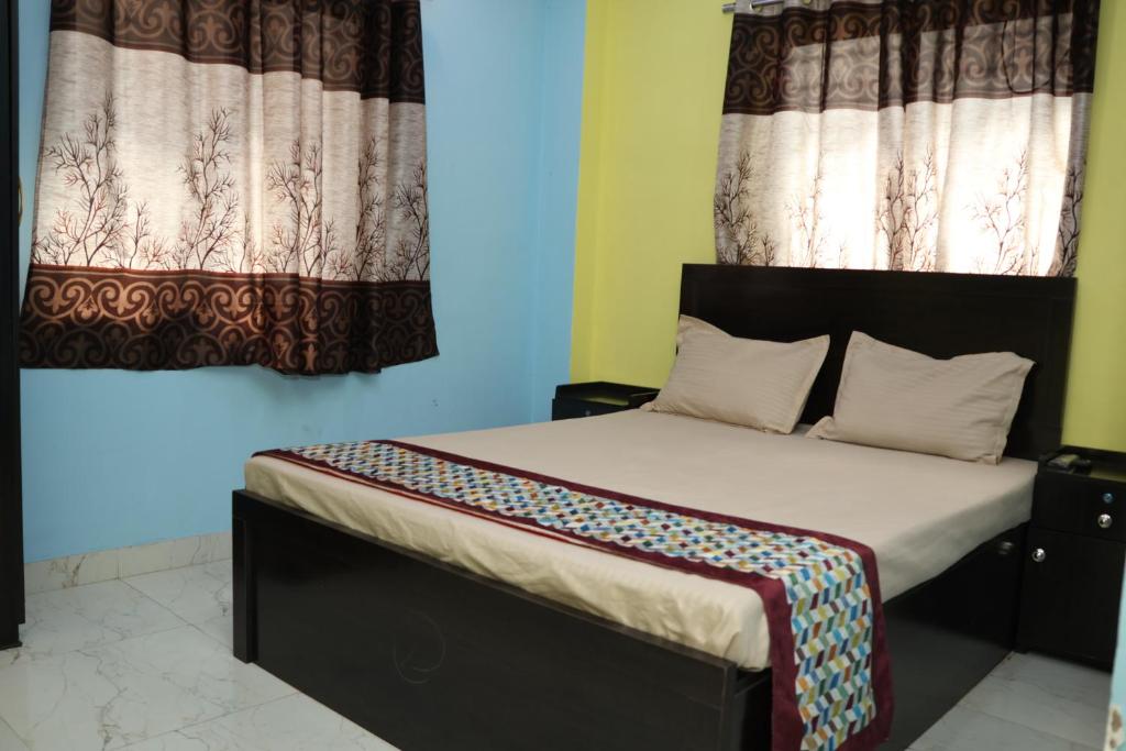 a bed in a room with two windows at Park kasba Inn in Kolkata
