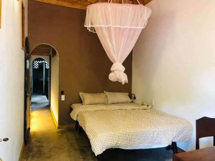 a bedroom with a bed with a curtain above it at LUX HOME Phước Hải in Hội Mỹ