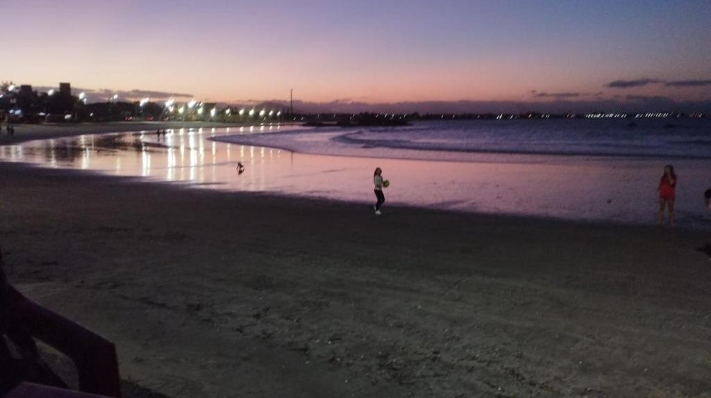 a person walking on the beach at sunset at Apto frente pro mar 3 pedra in Itapoa