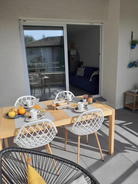 une table et des chaises en bois dans un salon dans l'établissement Le Lotus de Jade Bel appartement avec terrasses 2 chambres Résidence avec piscine, à Saint Cyprien Plage
