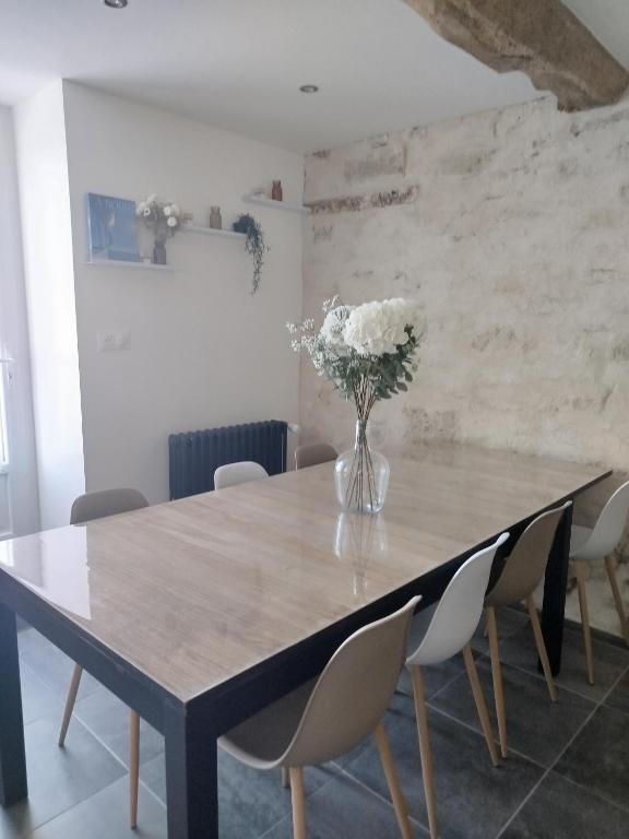 une table à manger avec des chaises et un vase de fleurs dans l'établissement Gîte du Doué, à Saint-Malo-du-Bois