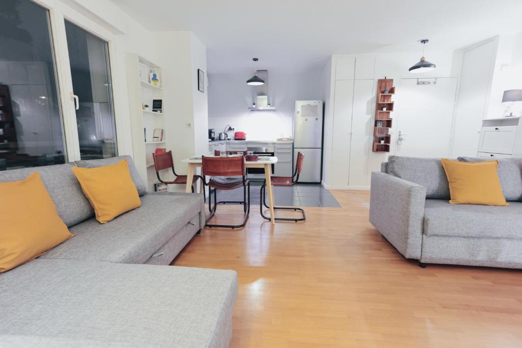 un salon avec un canapé et une table avec des chaises dans l'établissement Très Bel Appartement Neuf Quartier OPERA BASTILLE NATIONAL DE PARIS ET ATELIER DES LUMIERES, à Paris
