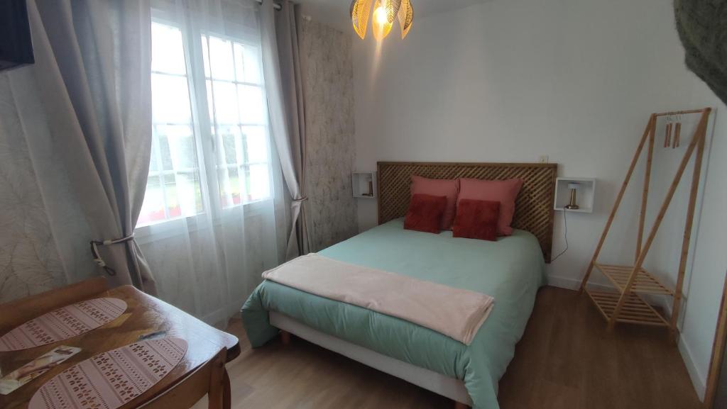 - une petite chambre avec un lit et des oreillers rouges dans l'établissement Studio jardin st jean de daye, à Saint-Jean-de-Daye