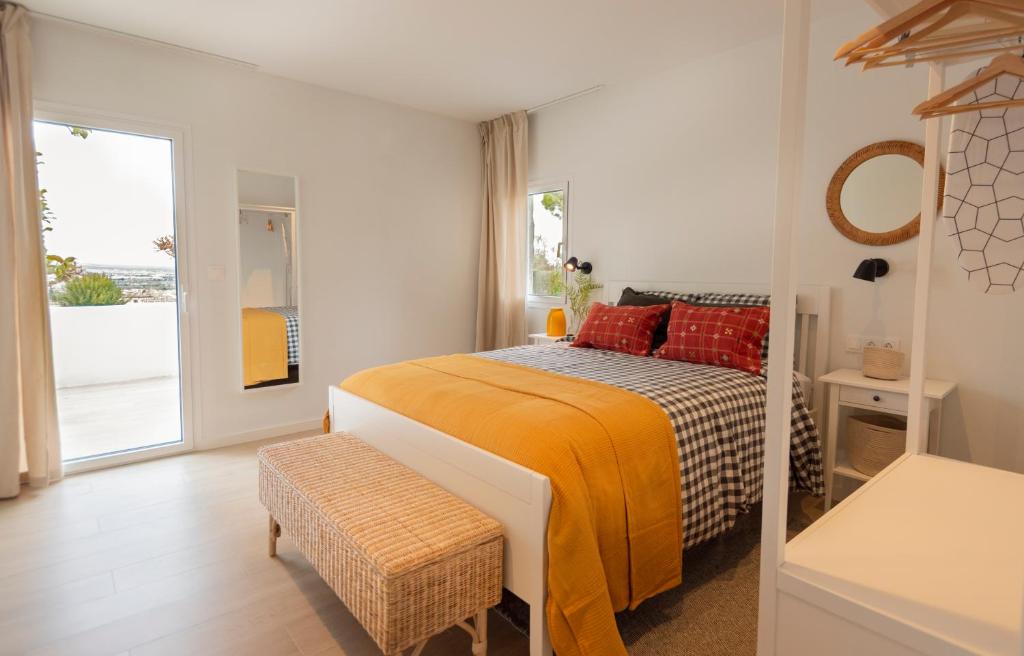 1 dormitorio con cama con sábanas de color naranja y ventana en Apartamentos La Guardilla, en Monachil